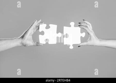 Mano di primo piano del puzzle di collegamento. Soluzioni aziendali, successo e concetto strategico. Due mani cercando di collegare il pezzo di puzzle coppia sul grigio Foto Stock