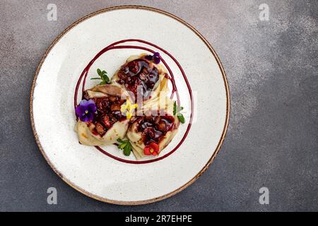 Primo piano di un piatto di frittelle fresche con farcitura e decorate con fiori Foto Stock