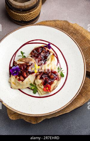 Primo piano di un piatto di frittelle fresche con farcitura e decorate con fiori Foto Stock