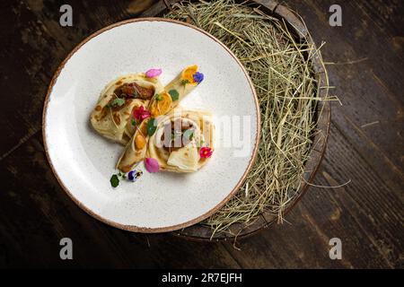 Un piatto bianco con frittelle appena cucinate adagiato su un letto di fieno, pronto per essere servito Foto Stock