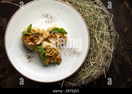 Un piatto bianco con frittelle appena cucinate adagiato su un letto di fieno, pronto per essere servito Foto Stock