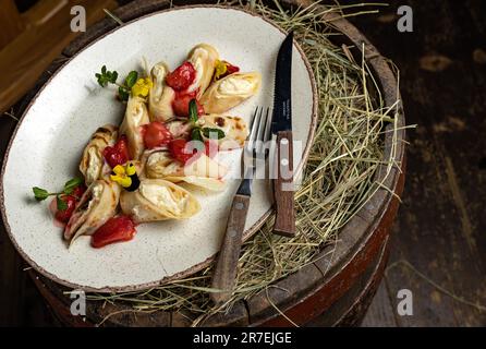 Un piatto bianco con frittelle appena cucinate adagiato su un letto di fieno, pronto per essere servito Foto Stock