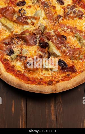 Pizza con salsa di pomodoro, selezione di formaggi misti, prosciutto, peperoni, pancetta, funghi freschi e olive. Foto Stock