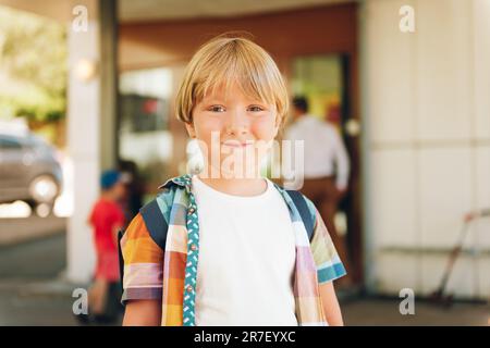 Ritratto all'aperto di adorabile ragazzino pronto a tornare a scuola, indossando una camicia colorata e uno zaino Foto Stock