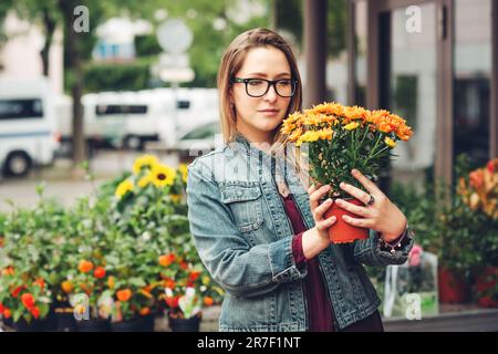 Donna che acquista fiori in pentole in negozio di fiori Foto Stock