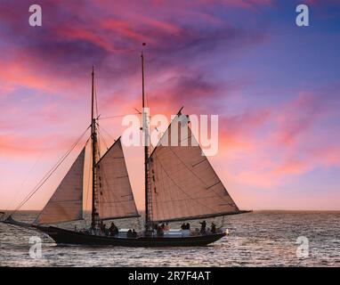 Una maestosa barca a vela si affaccia su uno splendido tramonto blu e rosa sull'oceano. Foto Stock