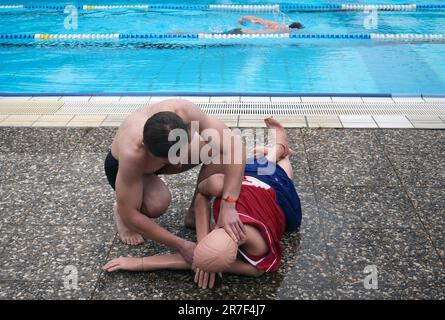 14 giugno 2023, Berlino: Alexander, di 25 anni, dimostra i metodi per risuscitare una vittima (posizione laterale stabile) su un manichino durante il nuoto preliminare di potenziali bagnini presso la piscina estiva Humboldthain. Le piscine all'aperto di Berlino sono ancora alla ricerca di bagnini per l'attuale stagione estiva. Devono sostenere il personale già esistente. Le parti interessate sono state in grado di presentare le proprie competenze durante la prima nuotata. A questo scopo, dovevano completare un esercizio di salvataggio combinato in cui un manichino di salvataggio veniva recuperato dall'acqua e veniva dimostrata una rianimazione. (A dpa: "Bäder-Betri Foto Stock