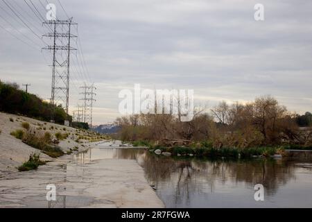 Una vista panoramica di un fiume, che si snanda attraverso una valle con linee elettriche sullo sfondo Foto Stock