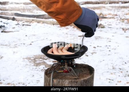 Salsicce in ciotola nella foresta in inverno. Camping alimentare. Cibo per viaggiatori in attività all'aperto. Foto Stock