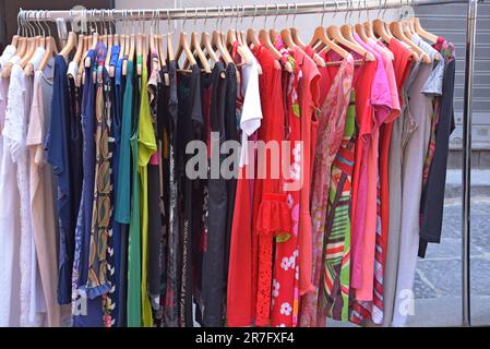 Abiti vivaci e colorati e altri abiti in vendita al mercato dell'abbigliamento vintage e retrò di Pugliano, a Ercolano, Napoli Foto Stock