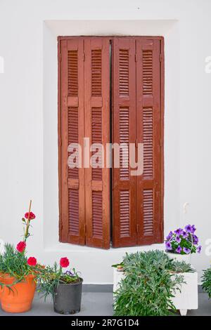 Persiane in legno e vasi di fiori di fronte a una vecchia casa tradizionale nella città di Lindos, sull'isola di Rodi, le isole greche dei Dodecani Foto Stock