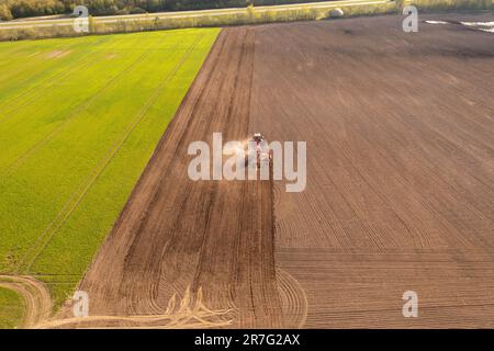 Fotografia in drone di macchine agricole che lavorano in campo coltivato durante la giornata di sole primaverile Foto Stock