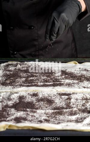 Processo di preparazione di una torta Napoleone con semi di papavero e ciliegie. Primo piano Foto Stock