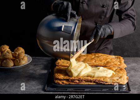 Processo di preparazione di una torta Napoleone con semi di papavero e ciliegie. Primo piano Foto Stock