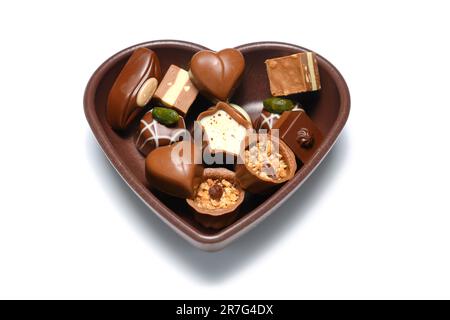 Cioccolatini colorati in un recipiente a forma di cuore. Su sfondo bianco. Foto Stock