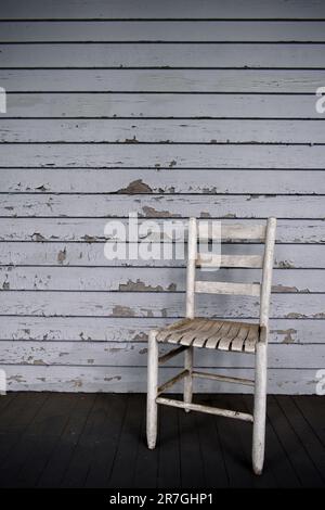 Sedia di legno sporca su avvolgere intorno portico anteriore Foto Stock