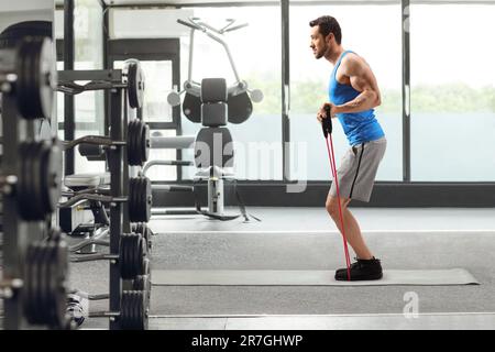 Immagine a tutta lunghezza di un uomo che si esercita con una fascia di resistenza in palestra Foto Stock