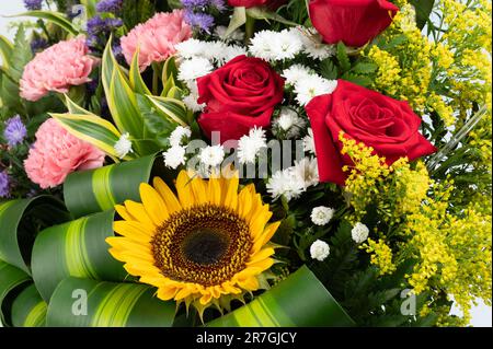 Colorato bouquet di fiori con rose e girasole su sfondo verde foglia Foto Stock