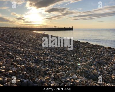 Guardando attraverso una pila decorativa di diverse pietre colorate, ciottoli e ciottoli a Hampton Stone Beach, Hampton Pier in lontananza. Foto Stock