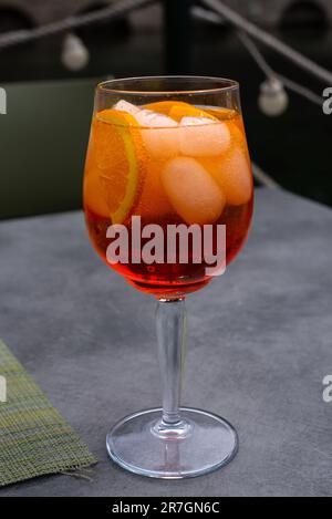 Primo piano del vetro con Spritz. Cocktail color arancio, cubetti di ghiaccio e fette di frutta arancione. Bevande alcoliche al bar. Aperol Foto Stock