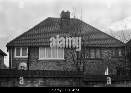 Un uomo guarda sopra il suo muro del giardino ad una dimostrazione, come il fronte Nazionale marcia attraverso il suo sobborgo di Manchester, insieme con un contromarro della Lega Ani-nazista. Manchester, Inghilterra, ottobre 8th 1977. 1970S REGNO UNITO HOMER SYKES Foto Stock