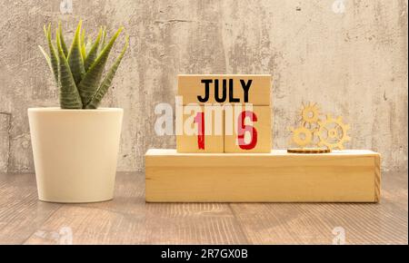 Calendario del 16 luglio, in cubetti di legno, su sfondo grigio.con uno spazio vuoto per il testo Foto Stock