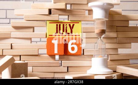 Calendario del 16 luglio, in cubetti di legno, su sfondo grigio.con uno spazio vuoto per il testo Foto Stock