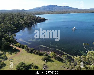 Una vista panoramica aerea di un oceano tranquillo circondato da colline maestose e vegetazione lussureggiante, l'isola di Maria Foto Stock