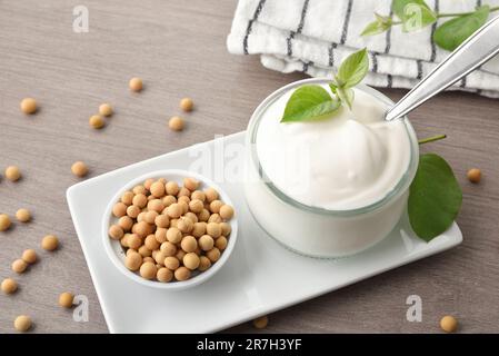 Bicchieri con yogurt a soia e ciotola con cereali su piatto bianco su banco da cucina in legno. Vista rialzata. Foto Stock
