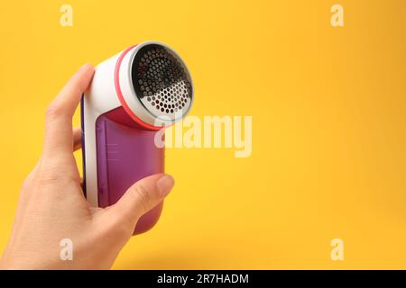Donna che tiene un rasoio moderno su sfondo giallo, primo piano. Spazio per il testo Foto Stock