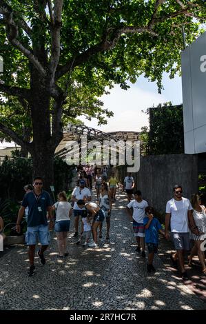 I turisti passeggiano per l'area all'aperto sulla cima della collina di Urca nel quartiere di Urca, vicino alla zona ristoro sotto il cielo soleggiato estivo nuvoloso del pomeriggio. Foto Stock