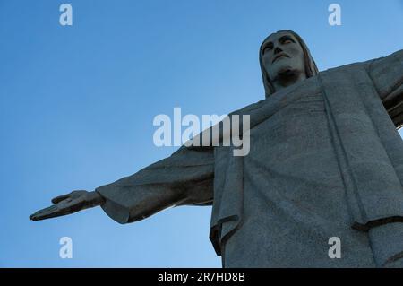 Guardando verso l'alto il lato anteriore destro della statua del Cristo Redentore situata sulla cima del monte Corcovado sotto il cielo azzurro e soleggiato d'estate. Foto Stock