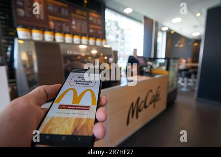 HO chi MINH CITY, VIETNAM - CIRCA MARZO 2023: Il segno Golden Arches visto sul touch screen dello smartphone al ristorante fast food McDonald's di ho Chi Foto Stock