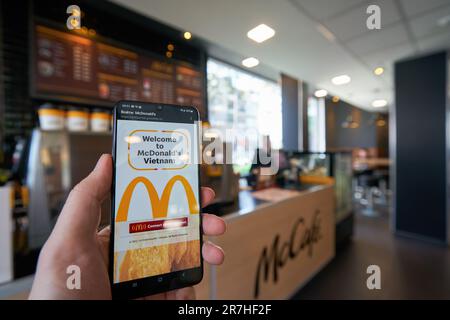 HO chi MINH CITY, VIETNAM - CIRCA MARZO 2023: Il segno Golden Arches visto sul touch screen dello smartphone al ristorante fast food McDonald's di ho Chi Foto Stock