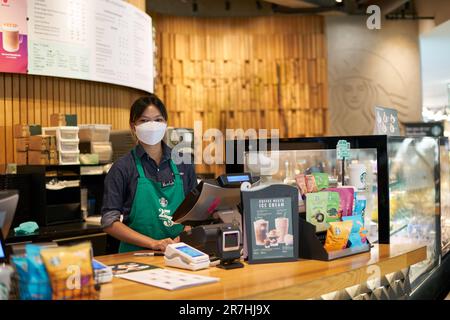 BANGKOK, THAILANDIA - CIRCA APRILE 2023: Ritratto al coperto di un dipendente, guardando la fotocamera, presso Starbucks Coffee nel centro commerciale Siam Discovery. Foto Stock