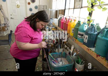 Asheville, Carolina del Nord, Stati Uniti. 9th giugno, 2023. Nicole Rotundo, che ha la sindrome di Down, cerca il pennello adatto per il suo progetto all'Open Hearts Art Center, uno studio di supporto e una galleria senza scopo di lucro che funziona anche come centro diurno. Il centro rappresenta e consente agli adulti con disabilità diverse di raggiungere il loro pieno potenziale attraverso le arti (Credit Image: © Robin Rayne/ZUMA Press Wire) SOLO PER USO EDITORIALE! Non per USO commerciale! Foto Stock