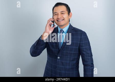 L'uomo d'affari parla al telefono con un sorriso sul viso, gli abiti in un abito dell'imprenditore, una persona Foto Stock