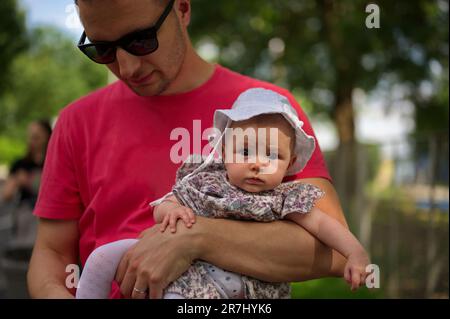 Padre che cammina in un parco e tiene piccola bambina Foto Stock