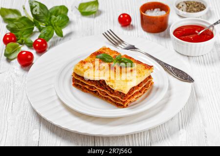 porzione di lasagna al forno, lasagne di manzo italiano a strati con macinato di manzo, salsa marinara, tagliatelle di pasta e ricotta su piatto bianco su piatto bianco Foto Stock