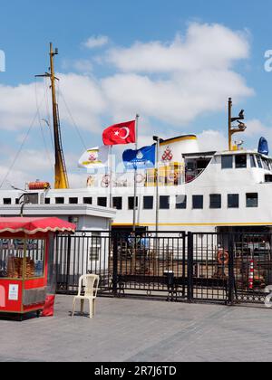 Traghetto a Eminönü a Istanbul, Turchia, con una bancarella rossa lasciata su un cielo blu e una giornata nuvolosa Foto Stock