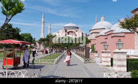 La Signora cammina lungo il percorso verso la Moschea di Santa Sofia. Il carrello rosso vende Simits, detto anche bagel turchi. Istanbul, Turchia Foto Stock