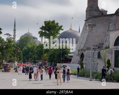 I visitatori accanto a Hagia Sophia e alla Moschea del Sultano Ahmed (conosciuta anche come Moschea Blu), Istanbul, Turchia. I carrelli distributori automatici rossi vendono Simit, ovvero bagel turchi Foto Stock