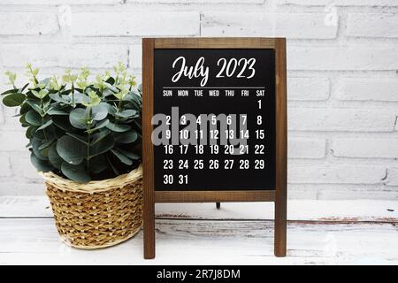 Luglio 2023 calendario mensile con decorazione a foglia verde su sfondo in legno Foto Stock