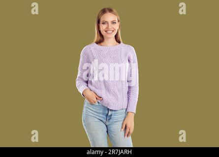 Bella giovane donna felice bionda vestita in maglia maglione e jeans blu chiaro guardando la macchina fotografica. Foto Stock