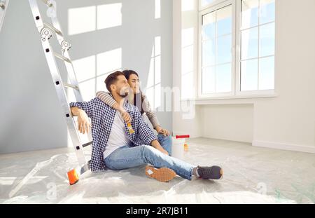 Felice coppia di famiglia che si rilassa al piano durante i lavori di ristrutturazione nella loro casa o appartamento Foto Stock