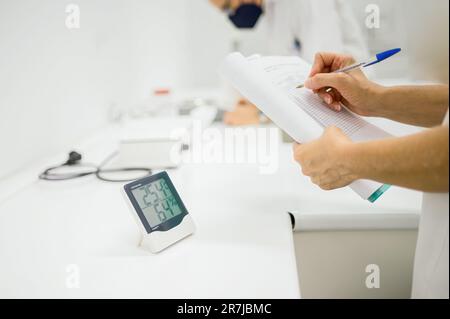Il farmacista prende appunti durante il controllo della temperatura e dell'umidità in laboratorio Foto Stock