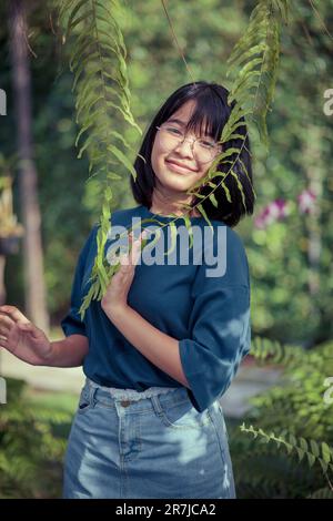 adolescente asiatico rilassarsi nel giardino botanico felce Foto Stock