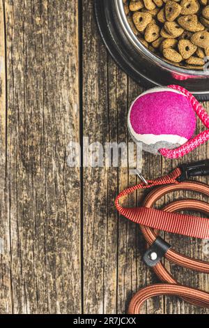 Cane piombo, giocattolo e cibo secco sul tavolo di legno. Vista dall'alto. Foto Stock