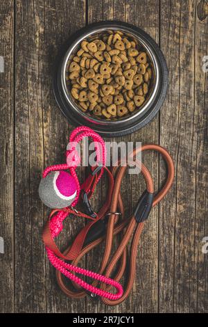 Cane piombo, giocattolo e cibo secco sul tavolo di legno. Vista dall'alto. Foto Stock