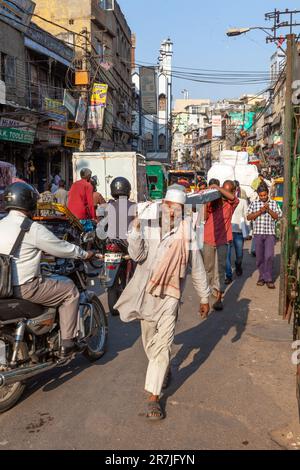 Nuova Delhi, India - 17 novembre 2011: vita di strada al più antico mercato Chandni Chowk nella vecchia Delhi. Le persone che portavano il goodsed la loro spalla al Meena Bazaar Foto Stock